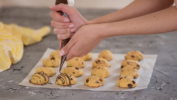 Female Chef Decorating Pumpkin Cookies with Melted Chocolate
