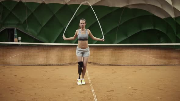 A Beautiful Brave Girl is Practicing Hard with a Skipping Rope on a Tennis Court alt
