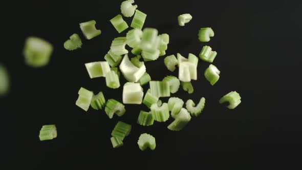 Fresh Green Celery Pieces Falling Down On A Black Surface