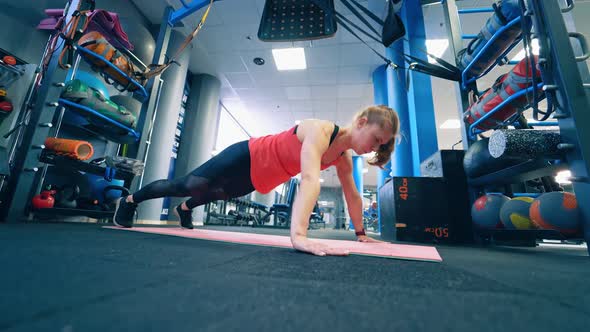 Athletic woman does push-ups as part of workout. alt