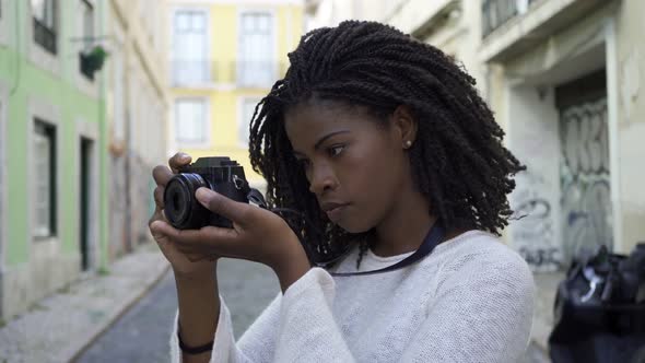 Cheerful Young Tourist Girl Taking Pictures in Old City Street alt