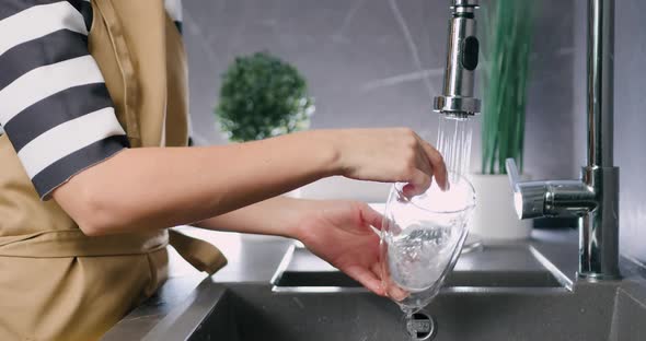 Close up of Caucasian Female Hands Washing Glass Dishes Under Water Jet at Modern Home Kitchen alt