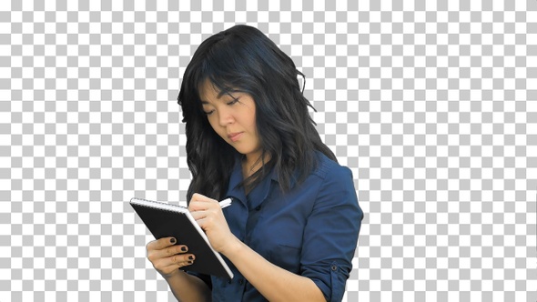 Pensive asian woman makes some notes in notepad, Alpha Channel