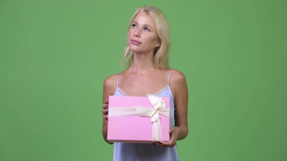 Young Happy Beautiful Businesswoman Thinking While Holding Gift Box