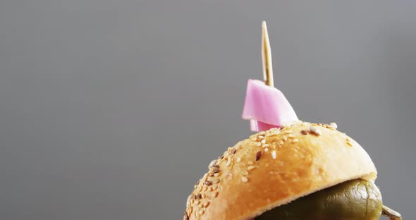 Hamburger on wooden board against grey background alt