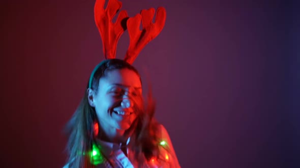 Young Woman in Christmas Mood Wearing Reindeer Antlers and Dancing alt
