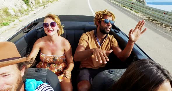 Blonde woman and black man riding in the back of convertible, color graded alt