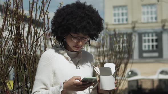 Woman Uses Smartphone While Eating Outdoors alt