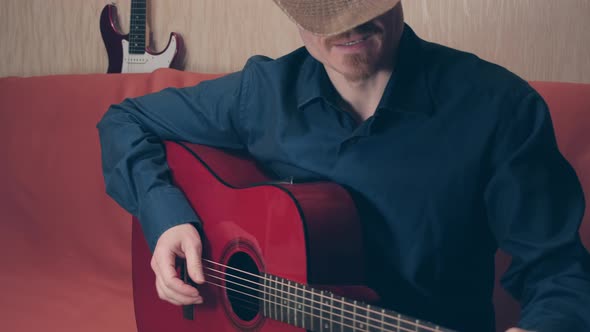 Man in Cowboy Hat Plays Red Acoustic Guitar and Sings