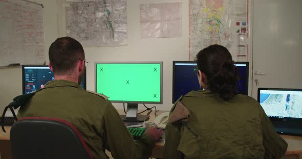 Israeli soldiers in a military command and control room looking at screens alt