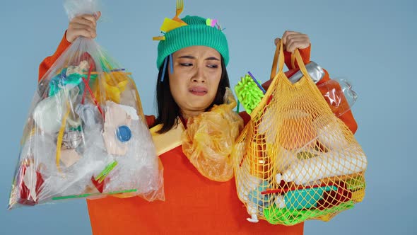 woman holding two packages full of garbage.