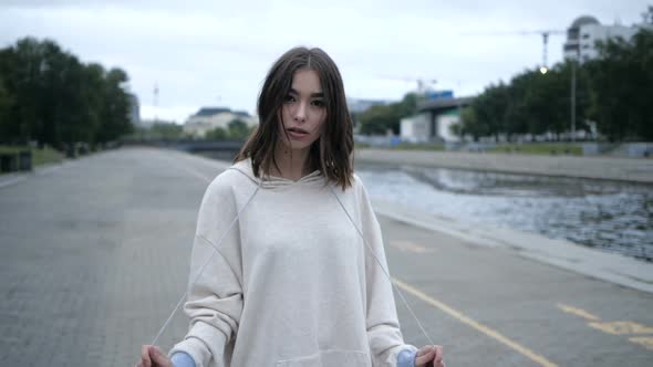 Beautiful Brunette, Looks at the Camera, Against the Background of an Empty City alt