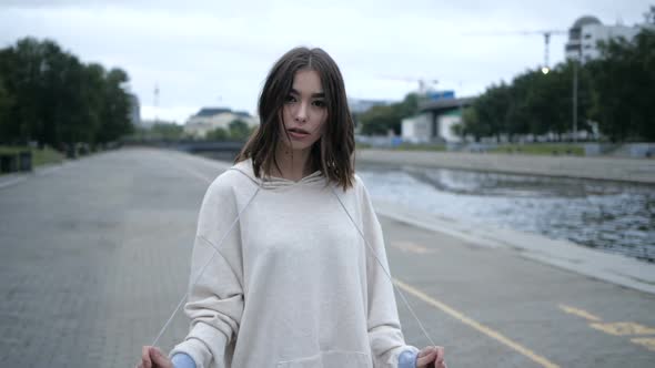 Beautiful Brunette, Looks at the Camera, Against the Background of an Empty City
