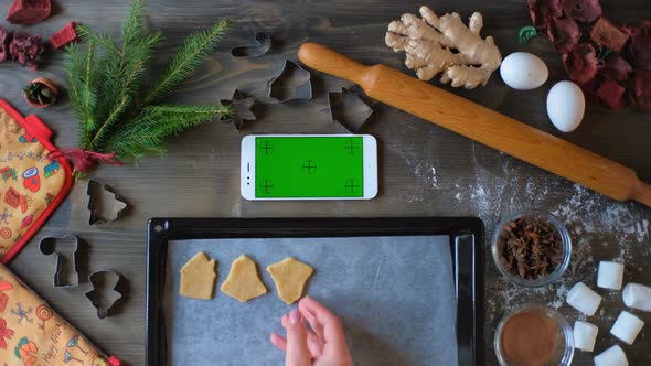 A Woman Lays Out Christmas Gingerbread Cookies Whit Green Screen Smartphone
