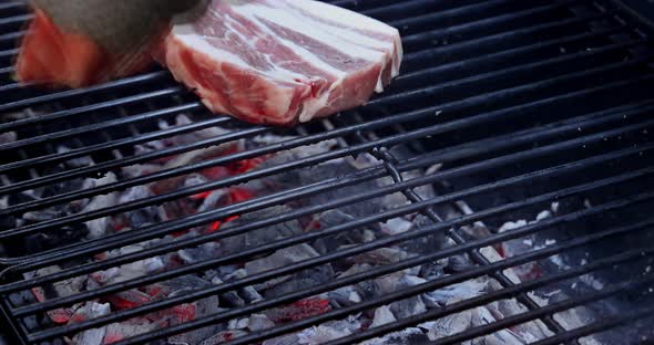 Juicy raw pork steak fried fire coals grill in the flame of smoke alt