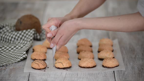 Chocolate Sauce Being Poured Over Coconut Macaroons on Parchment Paper