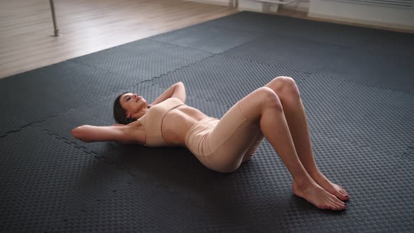 Attractive Slim Woman in Sportswear Doing Abs Exercise Lying on Floor in Gym alt