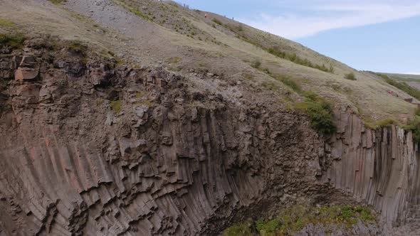 Steep Cliff in Studlagil Canyon and Mountain Silhouette in the Background alt