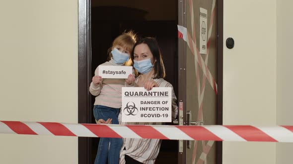 Sick Mother with Kid Daughter in Medical Masks Opening Home Door Coronavirus Quarantine Lockdown alt