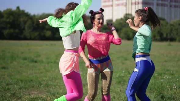 Three Excited Retro Women Having Fun Dancing Jumping in Slow Motion on Sunny Meadow Outdoors alt