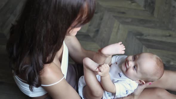 Happy Young Mother Talking Playing with Her Infant Baby Child on Floor in Room alt