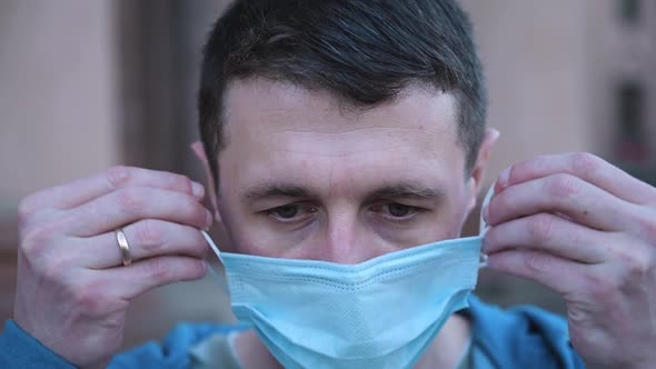 Close Up Portrait of Caucasian Man Putting Medical Mask on Face