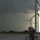 Woman Rides Bicycle Along Wide Asphalt Road By Windmills - VideoHive Item for Sale