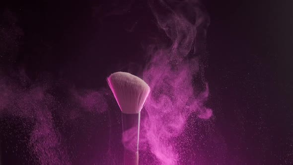 Close Up Shot of Two Makeup Brushes Being Rubbed Together and Scattering Pink Shimmer Powder on Dark