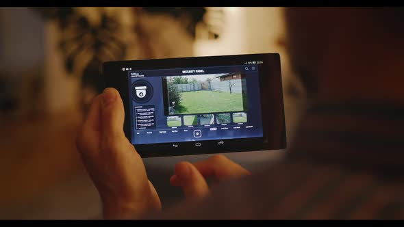 Man Checking Security Camera Through Home Hub alt