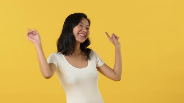 Energetic happy young Asian woman smiling and dancing