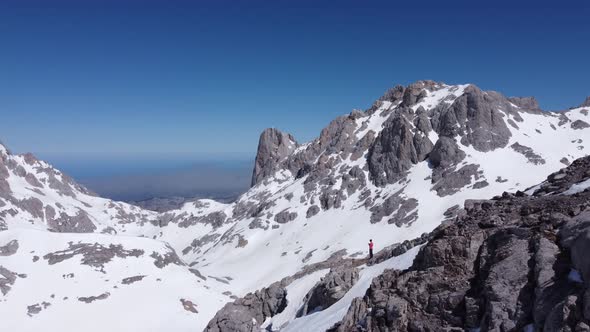 Anonymous traveler with drone on Picos de Europa mountains covered with snow alt