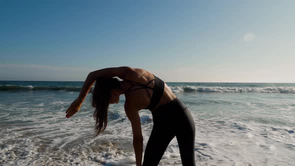 Athletic woman at the beach stretching and relaxing after her workout alt