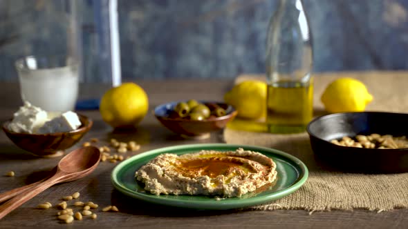 Warm, low angle slide to the right showing middle eastern food spread of olives, pine nuts, hummus, alt