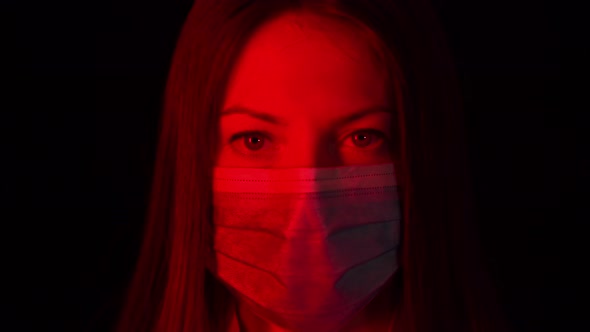 Close Up of Doctor's Eyes in a Mask. Serious Look of a Nurse During Pandemic. Young Woman in Red