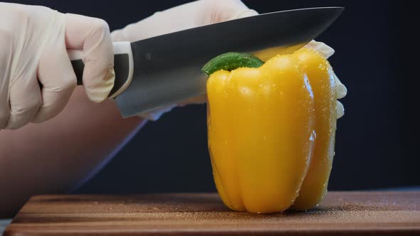 Person in White Gloves Cuts Yellow Bell Pepper with Knife alt
