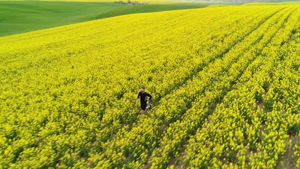 A Man Runs Sportively on a Yellow Spring Rapeseed Field