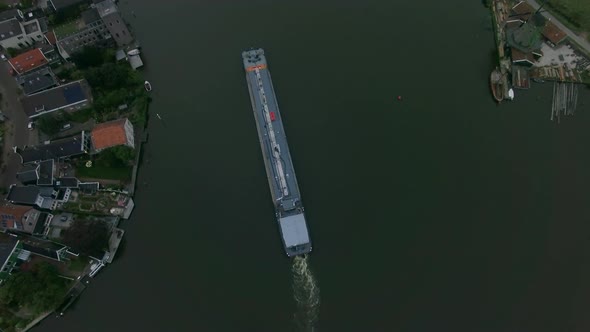 Aerial shot of barge sailing down the river in town alt