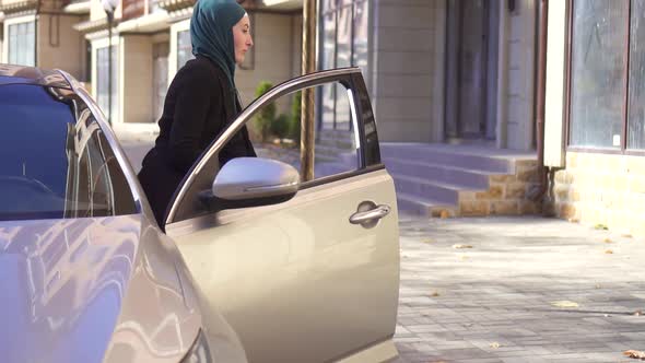 Muslim Woman in Hijab with Phone in Hand Out of the Carslow Mo