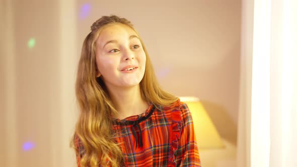 Charming Pretty Little Girl Looking Out the Window Smiling Waving with Christmas Lights Flashing at alt