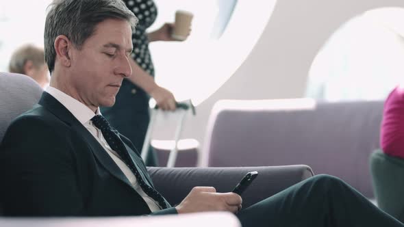 Business man waiting in airport lounge on mobile phone