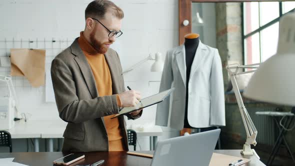 Male Designer Drawing New Garment Sketch Using Modern Tablet Working in Studio alt