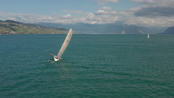Wide Aerial of man hanging overboard on sailboat in order to steady the vessel alt