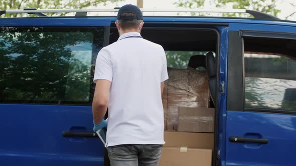 A Delivery Man Uses a Tablet Near the Van alt