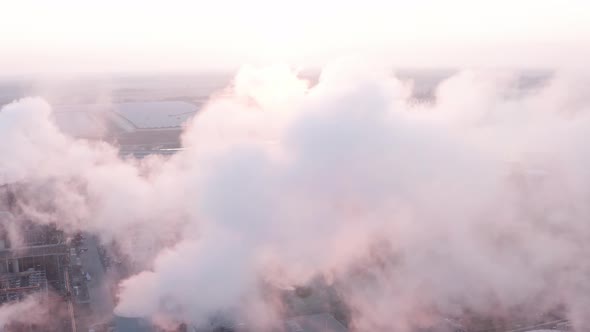 Aerial view during sunrise of steel factory powered by solar panels. Flying into the exhaust smoke alt