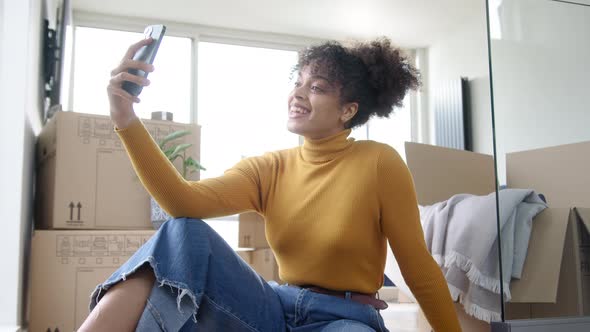 Woman Holding Keys With Mobile Phone Moving Into New Home Making Video Call Surrounded By Boxes