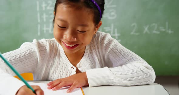 Schoolgirl doing homework in classroom at school alt