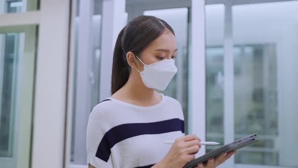 asian woman business owner wear mask use tablet checking amount of stock product