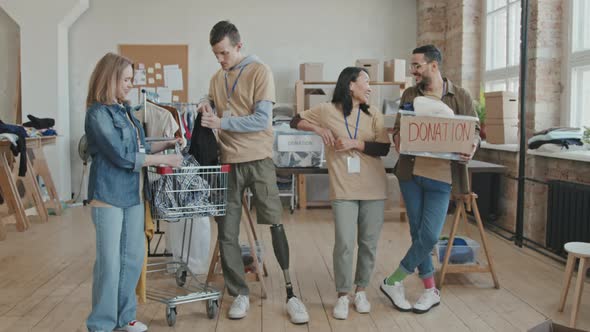 Portrait of Cheerful Volunteers Sorting out Clothes for Charity alt