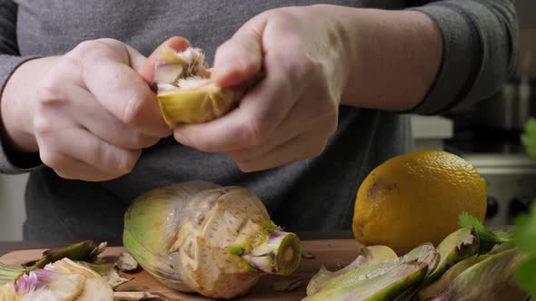 Woman Cleaning Heart of Artichokes with Spoon alt