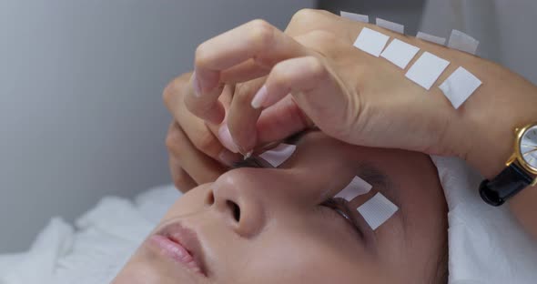 Woman having eyelash extension in beauty salon alt